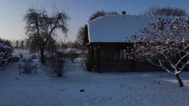 Beyaz Rusya 'da kışın kardan sonra bir köyün havadan görünüşü. Karla kaplı eski ahşap çiftlik evi. Hava manzaralı. Şafak vakti köy manzarası