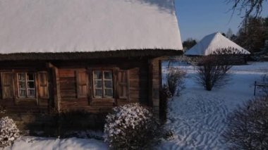Kış köyünde güneş doğuyor. Kışın güneş batarken ahşap çiftlik evi. Drone köyün ahşap evinin önünden uçuyor. Hava görüntüsü. Beyaz Rusya