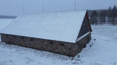 Hava sahasında Eski Taş Ahır Bölge Tepesi Kar Tepesi Belarus. Eski taş ahır. Avrupa 'da bir çiftlikte karla kaplı bir ahır. Ahırın çatısına yıldırım çubukları yerleştirildi.