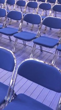 Seminerden, konserden, ön seçimlerden önce boş mavi sandalyelerin dikey yakın çekimi. Geçici seyirci koltukları. Metal katlanır sandalyeler. kamera hareketleri