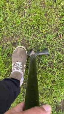 Dikey video görüntülü adam kürekle toprağı kazıyor. Bir işçi toprağı kazar. Adam yerde çimlerle bir çukur kazmaya başlıyor. Çiçek ekmek için toprağı kazmak, bir bahçe kazmak.