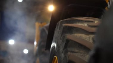 Garajda traktör çalışıyor. Garajdaki traktör motorunu ısıtıyorum. Motor çalıştı. Traktör lastik izinin yakın çekimi. Tekerlek duman içinde. Kırık kamyon lastiği.