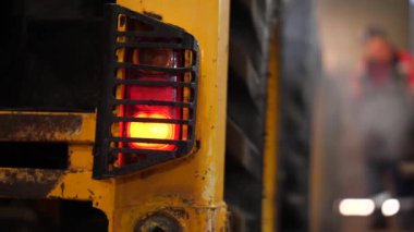 Traktörün arka ışıklarına yakın çekim. Garajda traktör çalışıyor. Garajdaki motoru ısıtıyorum. motor başlat