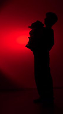 vertical video Person silhouette balancing a tall stack of books, representing knowledge, education, and the heavy academic burden on a student, dramatically backlit by a red spotlight