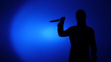 Koyu mavi arkaplana bıçak dayamış silüet şeklinde bir figür. Tehditkar ve tehlikeli bir kavram getiriyor. Suç, şiddet ve tehdit temaları için mükemmel.