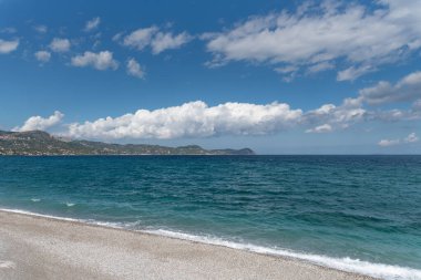 Mavi gökyüzü ve birkaç bulutu olan bir sahil.