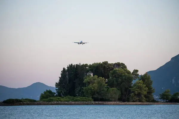 a plane flying over the small island of Pontikonisi in Corfy island Greece