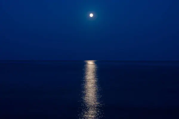 a full moon is reflected in the water on the night