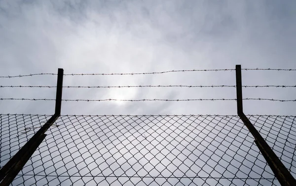 a fence with barbed wire and a sky background