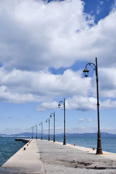 a pier with a row of street lights and a bench