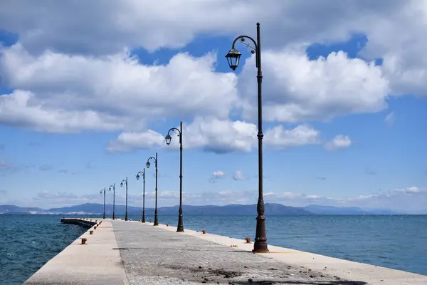 a pier with a row of street lights and a bench