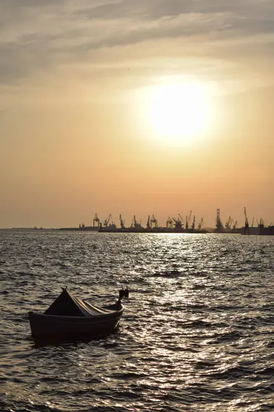 Günbatımında suda bir tekne ve Selanik, Yunanistan 'da arka planda bir şehir.