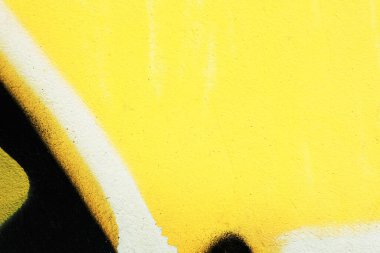 Duvar yazısı olan eski alçı bir duvar parçası. Duvardaki renkli sokak sanatı grafitisinin bir parçası. Gençlik, şehir kültürü. Sarı, siyah, beyaz renkler.