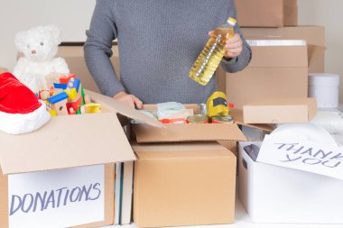 Hayır kurumu için Noel bağışları. Gönüllü olarak yiyecek, giyecek, çocuk oyuncağı, bağış kutularına kitap topluyor. Bağış, yardım, gıda bankası, düşük gelir için yardım, yoksul aileler, mülteciler, evsizler