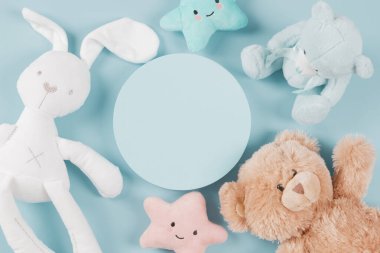 Bebek oyuncakları koleksiyonu. Boş platform podyumu, oyuncak ayılar, beyaz tavşan ve açık mavi arka planda şirin peluş oyuncaklar. Üst görünüm, alanı kopyala.