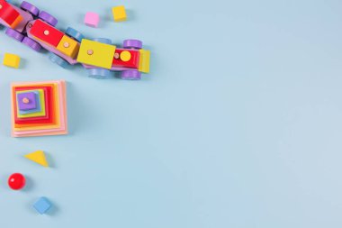 Bebek çocukların oyuncak geçmişi. Tahta tren, açık mavi arka planda renkli sürdürülebilir eğitim oyuncakları. Montessori, çocuklar için çevre dostu oyuncaklar. Üst manzara, düz uzanma.
