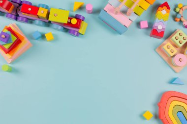Bebek çocukların oyuncak geçmişi. Tahta tren, açık mavi arka planda renkli sürdürülebilir eğitim oyuncakları. Montessori, çocuklar için çevre dostu oyuncaklar. Üst manzara, düz uzanma.