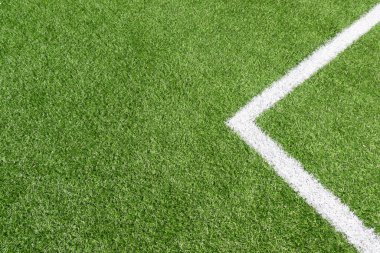 Beyaz çizgili yeşil futbol sahası çimlerinin üst görüntüsü.