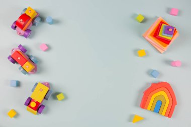 Bebek oyuncakları çerçeveli arka plan. Tahta tren, açık mavi arka planda renkli doğal ahşap eğitici oyuncaklar. Montessori, çocuklar için çevre dostu oyuncaklar. Üst manzara, düz uzanma.