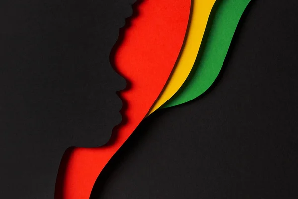 Black History Month color background. African Americans history celebration. Abstract geometric red, yellow, green color background with black paper cut people silhouette. Top view.