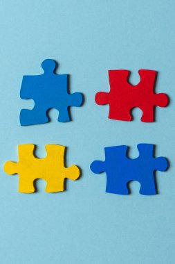Açık mavi arkaplanda mavi, sarı, kırmızı yapboz parçaları. Dünya otizm farkındalık günü konsepti. Üst görünüm, alanı kopyala.
