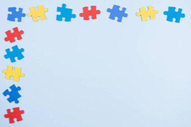 Açık mavi çerçeve arka planında mavi, sarı, kırmızı yapboz parçaları. Dünya otizm farkındalık günü konsepti. Üst görünüm, alanı kopyala.