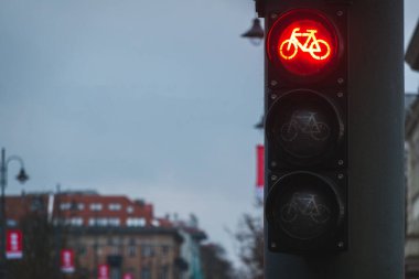 Bicycle traffic light with bicycle icon and active red resolving light. Bike traffic light on gray pole in the city at night.