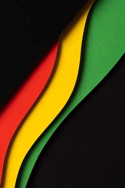 Black History Month color background. Abstract black, red, yellow, green color background with geometrical wavy lines and shapes. Top view.