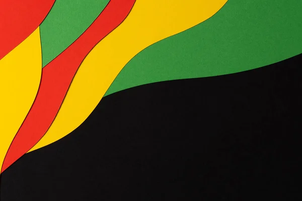 Black History Month color background. Abstract black, red, yellow, green color background with geometrical wavy lines and shapes. Top view.