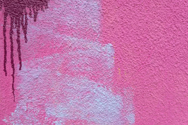 Pink, magenta, white painted plaster wall surface background with colorful drips, flows, streaks of paint and paint sprays