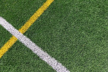 Yeşil yapay çimen sahası futbol sahası arka planı beyaz ve sarı çizgi sınırlı. Üst görünüm.