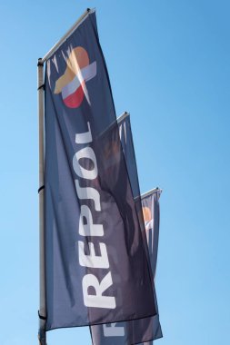 Vertical hanging blue fabric banner flag with Repsol logo sign. Repsol - Spanish energy and petrochemical company that develops, produces and markets lubricants, oil-based specialized products.