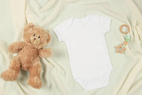 ベージュブランケットスローの背景に白い綿の赤ちゃんの短い袖のボディスーツ テディベアと自然の木製のおもちゃ 幼少期のモックアップ ブランク性別中性新生児の体のモックアップテンプレート トップ表示 — ストック写真