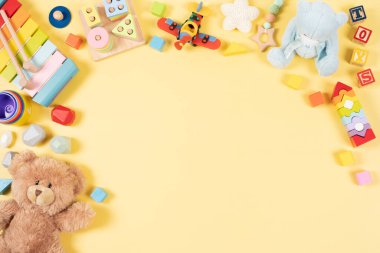 Bebek çocukların oyuncak çerçeve arka planı. Oyuncak ayı, renkli ahşap eğitici, müzikal, duyusal, pastel sarısı arka planda çocuklar için oyuncak sınıflandırma ve dizme. Üst manzara, düz uzanma.