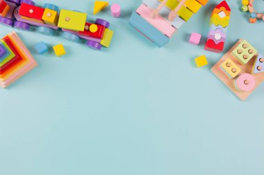 Bebek çocukların oyuncak geçmişi. Tahta tren, açık mavi arka planda renkli sürdürülebilir eğitim oyuncakları. Montessori, çocuklar için çevre dostu oyuncaklar. Üst manzara, düz uzanma.