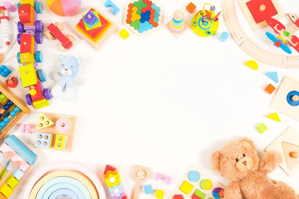 Baby kids toy background. Teddy bear, plush, wooden educational, musical, sensory, sorting and stacking toys, train, colorful building blocks on white background. Montessori toys. Top view, flat lay.