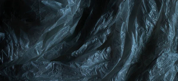 Dark plastic wrap background. Crumpled wrinkled plastic cellophane. Texture overlay effect template.