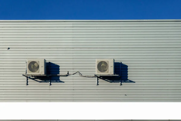 Two old air conditioner hangs on corrugated sheet metal wall of warehouse, storage, store. Industrial look. Outdoor.