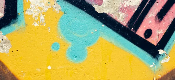 Detail of colorful graffiti wall. Old weathered colorful graffiti painted peeled plaster wall with falling off flakes of paint.