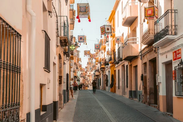 stock image Finestrat, Alicante, Spain - 23 March 2023: People enjoy sunny day in Finestrat. View to narrow street Carrer Nou in Finestrat old town.