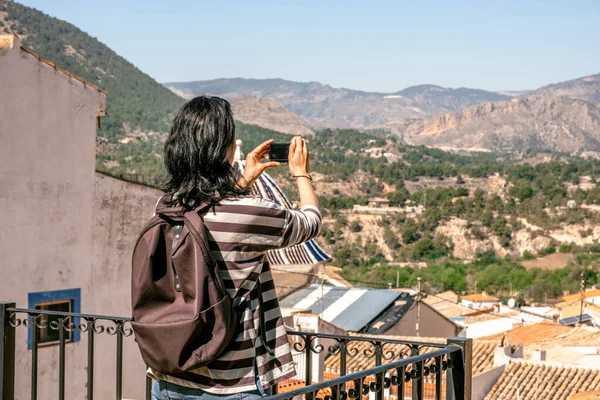 Finestat 'ın fotoğrafını çeken bir turist. Gezgin kadın manzara fotoğrafı çekmek için küçük bir kamera kullanıyor. Finestat, Alicante bölgesi, Costa Blanca, İspanya. Tek başına seyahat, tek başına tatil..