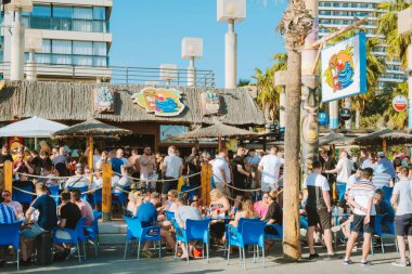 Benidorm, İspanya - 1 Nisan 2023: İnsanlar popüler Tiki sahil barında tatilin tadını çıkarıyor. Benidorm - Akdeniz yakınlarındaki popüler İspanyol tatil beldesi, Alicante ili, Costa Blanca, İspanya.