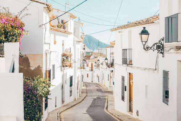 Cozy narrow street with whitewashed houses in Altea old town in sunny day. Architecture in small village of Altea near Mediterranean sea, Alicante province, Valencian Community, Spain.
