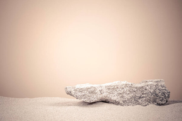 Grungy stone platform podium for cosmetics or products presentation on white beach sand and beige color background. Front view.