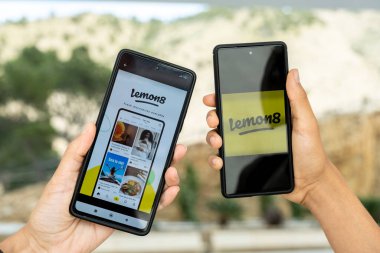 Benidorm, İspanya - 06 Nisan 2023: Limon8 uygulaması içerik paylaşım platformuna sahip iki akıllı telefon ekranda. Lemon8 ByteDance 'e ait video ve fotoğraf paylaşım sosyal medya uygulaması..