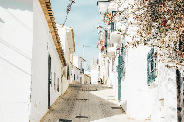 Cozy narrow street with whitewashed houses in Altea old town in sunny day. Architecture in small village of Altea near Mediterranean sea, Alicante province, Valencian Community, Spain.