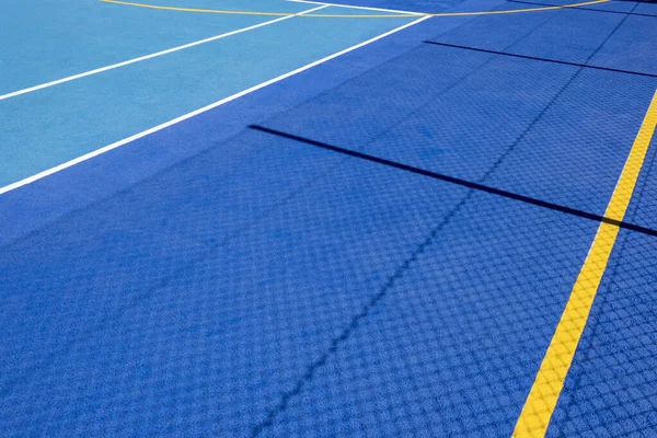 Sport field court background. Blue rubberized and granulated ground surface with white, yellow lines and tennis net shadow on ground. Top view.