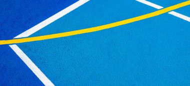 Spor sahası geçmişi. Mavi kauçuk ve granüle zemin yüzeyinde beyaz, sarı çizgiler var. Üst görünüm.