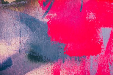 Messy paint strokes and smudges on an old painted wall background. Abstract wall surface with part of graffiti. Colorful drips, flows, streaks of paint and paint sprays.