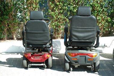 Benidorm, İspanya - 01 Mayıs 2023: Dört teker hareketli elektrikli scooter şarj ediliyor. Yaşlılar veya engelliler için kişisel ulaşım.